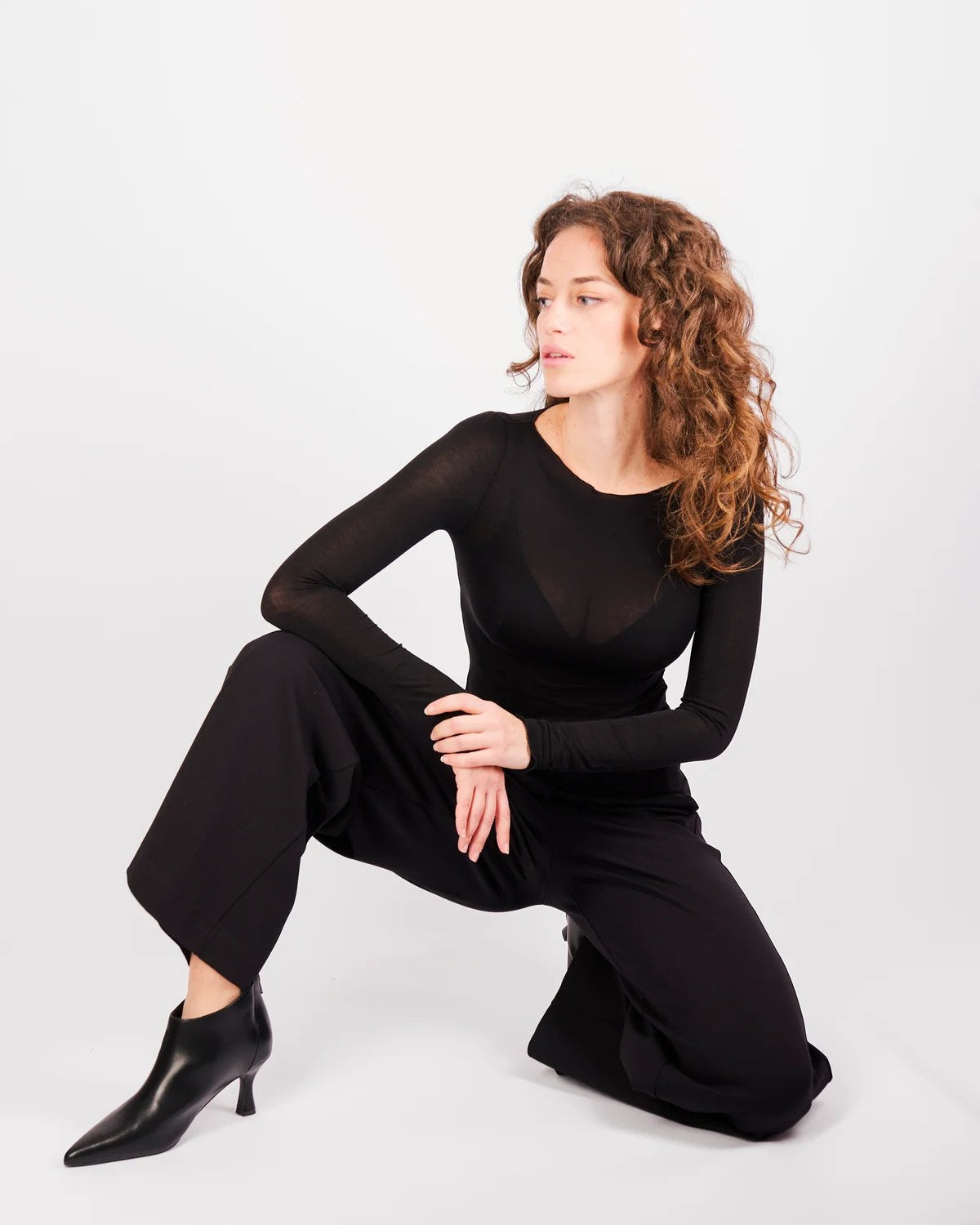 Donna indossa maglia ultraleggera scollo a barchetta blu semitrasparente con pantaloni neri a gamba larga