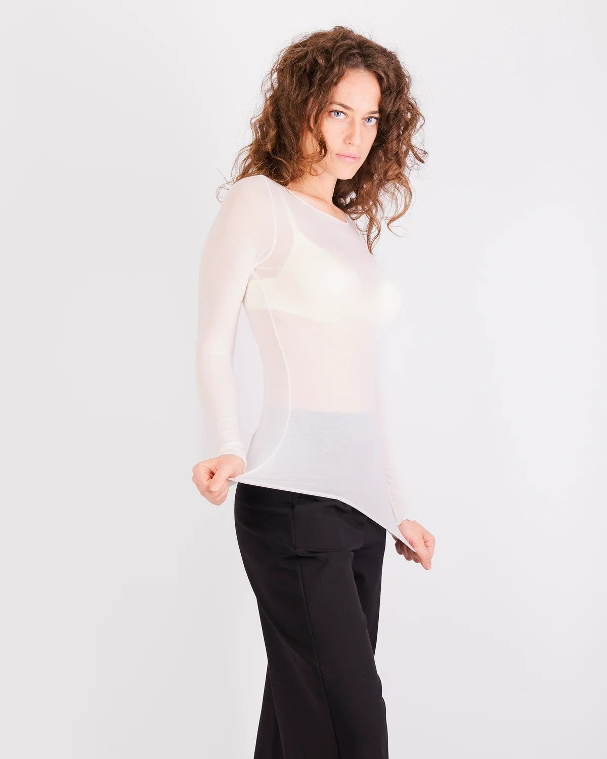 Donna indossa maglia ultraleggera scollo a barchetta blu semitrasparente con pantaloni neri a gamba larga