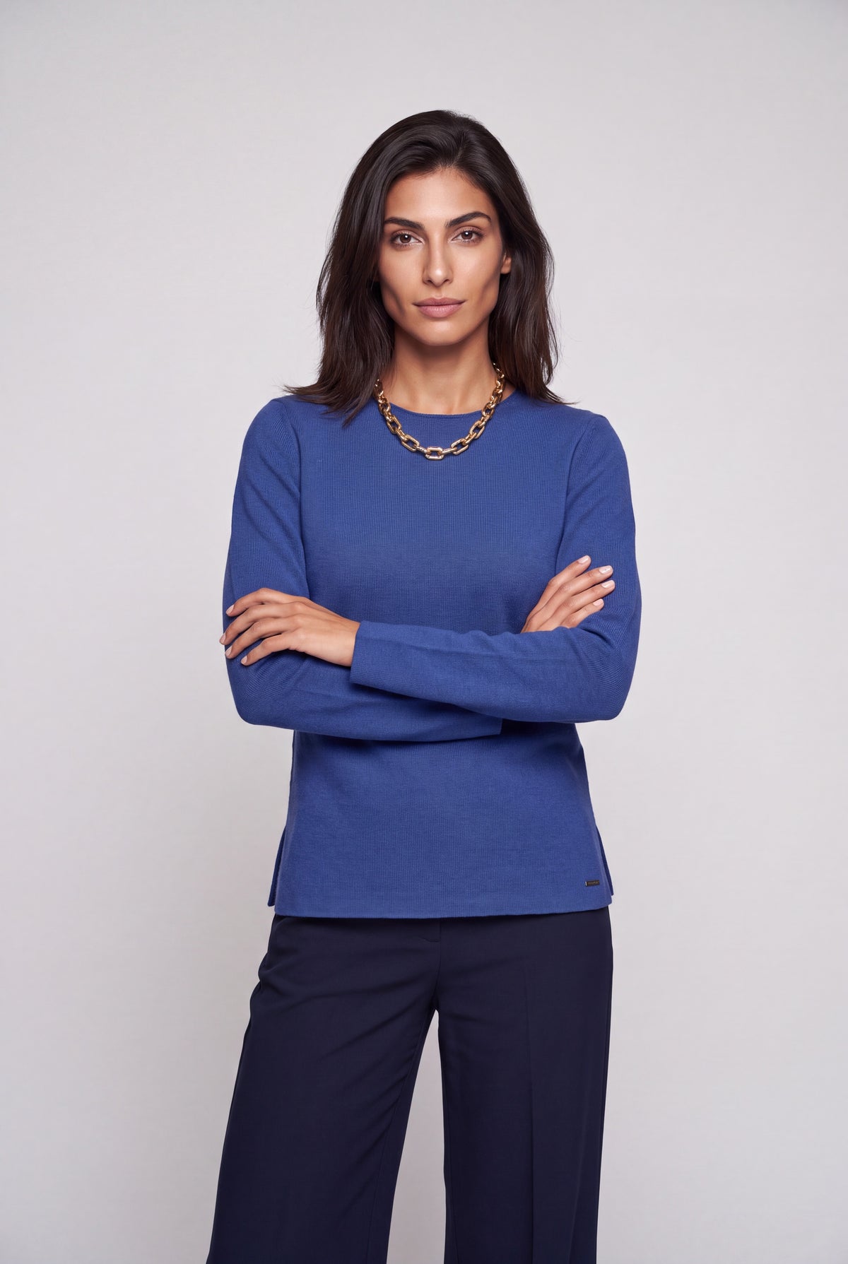 Maglia girocollo in pura lana verde con spacchetti laterali e lavorazione links, su sfondo neutro